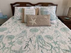 a bed with two pillows on top of it next to a night stand and lamp