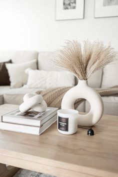 a coffee table with a vase, candle and books on it