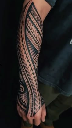 a man's arm with an intricate tattoo design on the arm and hand,