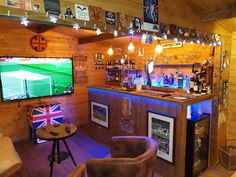 a bar with two chairs and a television on the wall in front of it that is lit up