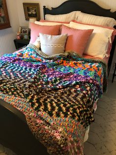 a crocheted blanket on top of a bed in a room with white walls