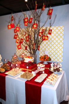 a table topped with cakes and desserts next to a tree