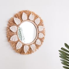 a mirror on the wall next to a potted plant and palm leaf decoration in front of it