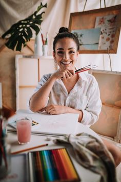 a woman sitting at a table with some art supplies