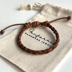 a close up of a bracelet on top of a cloth bag with a small logo