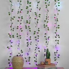 a table topped with a plant next to a wall covered in purple flowers and green leaves