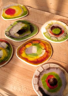 four plates with different colored food on them sitting on a table top next to each other