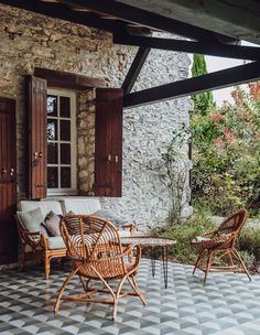 an outdoor seating area with chairs and tables on the floor next to a stone building