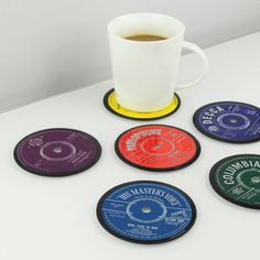 six coasters with various records on them and a cup of coffee in the middle