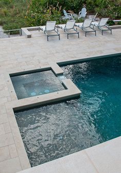 an outdoor swimming pool with chairs around it