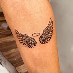 a tattoo on the leg of a person with an angel wing and halo above it