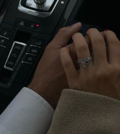 a man and woman are holding hands in front of a car radio with their wedding rings