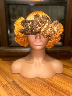 a mannequin head wearing a crocheted hat with flowers on it's side