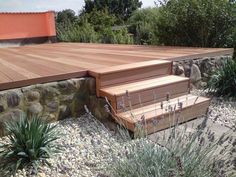 a wooden deck with steps leading up to it and plants growing on the ground next to it