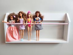 five dolls are lined up on a shelf