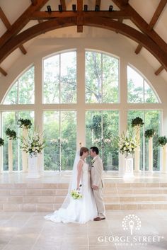 a bride and groom kissing in front of large windows