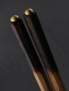 two wooden chopsticks sitting on top of each other in front of a black background