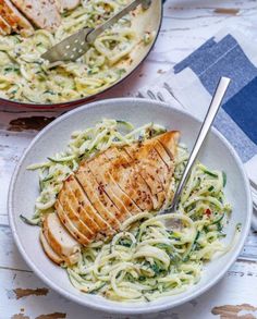 two bowls filled with pasta and chicken on top of a table