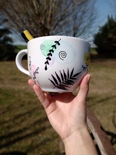 a hand holding up a coffee cup with an artistic design on the outside and inside