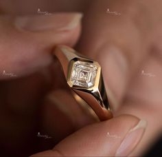 a close up of a person's hand holding a ring with a diamond in it