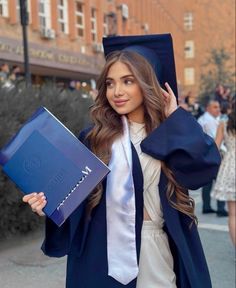 a woman in graduation gown holding a book