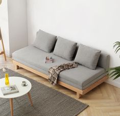 a grey couch sitting on top of a hard wood floor next to a white table