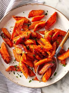 a white plate topped with sliced up sweet potato wedges next to a fork and napkin