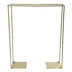 a pair of gold metal clothes racks with two shelves on each side and one standing upright