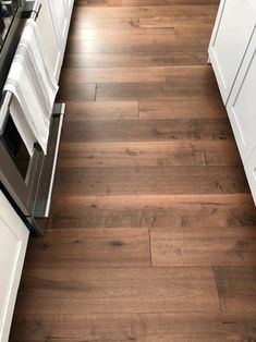 a kitchen with wood flooring and white cabinets in the corner, looking down at the stove