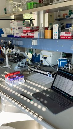 a laptop computer sitting on top of a desk next to a microscope and other items