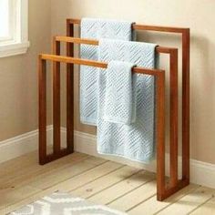 a towel rack with two towels on it in a bathroom next to a rug and window