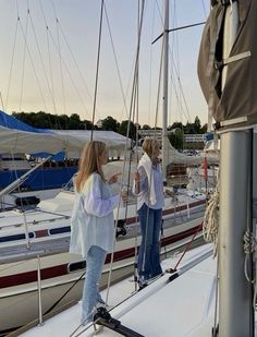 two women standing on the deck of a sailboat talking to each other while another woman stands next to her