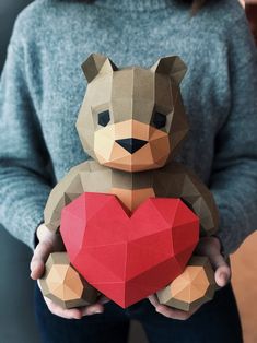 a person holding a heart shaped paper animal with the shape of a bear on it's chest