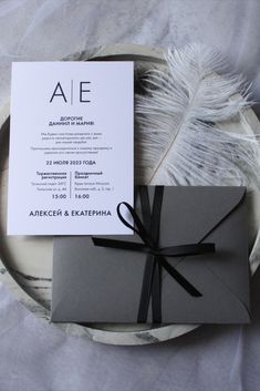 the wedding stationery is wrapped in black and white paper with a feather on it