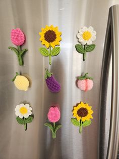 crocheted flowers are placed on the side of a stainless steel refrigerator freezer