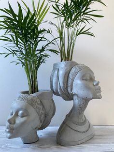 two ceramic heads with plants in them on a table