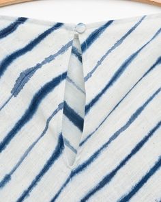 a tie is tied to a white and blue striped shirt on a wooden hanger