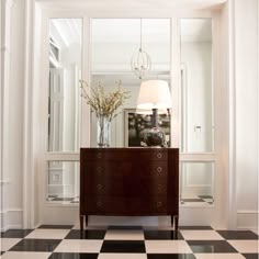 a room with black and white checkered flooring, a lamp and a dresser