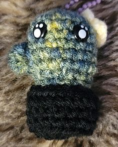 a crocheted stuffed animal with eyes on it's head sitting on a furry surface