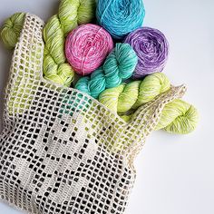 several skeins of yarn in a bag on a white surface with the handles off