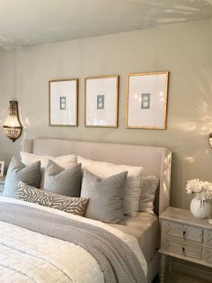 a white bed with gray pillows and pictures on the wall