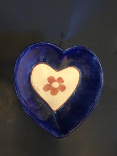 a blue heart shaped dish with an orange flower on the center and two hearts in the middle