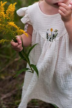 Natural muslin dress for little girls. It's made of high quality organic muslin. It has small hand-embroidered flowers on the front. The dress features flutter sleeves and a gathered tiered bottom. On the back it has a thin stripes with floral motives. This loose dress gives your child complete freedom and movement and it will look amazing. The colour of the dress in the photos is ecru. Long sleeves dress is available here: https://www.etsy.com/listing/1593987699 . All our items are handmade, hand cut and sewn, therefore pattern placements may vary slightly from the item pictured.  Washing instructions: Machine wash cold water 30oC / 104oF., wash with similar colours. Do not tumble dry. Do not bleach. Iron if you need, best on the inner side of the fabric. Muslin Dress Pattern, Girl Boho Dress, Baby Girl Boho, Girls Boho Dress, Floral Motives, Child Dress, Muslin Dress, Magic Dress, Boho Baby Girl