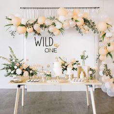 a table with white flowers and greenery on the top is set up for a wild one event