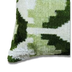 a green and white pillow on a white background with an abstract design in the middle