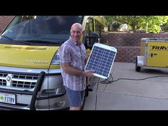 a man standing next to a yellow van holding a solar panel