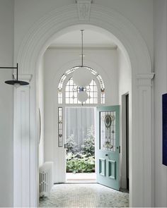 an archway leading to the front door of a house with blue and white tiles on the floor