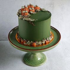 a green cake with pumpkins and leaves on top