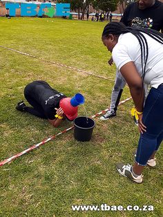 two people standing over a bucket on the ground