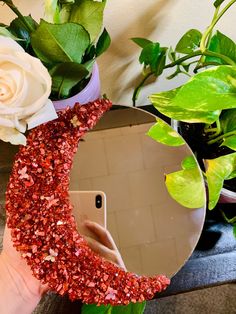 a person holding a cell phone in front of a mirror with red glitter on it